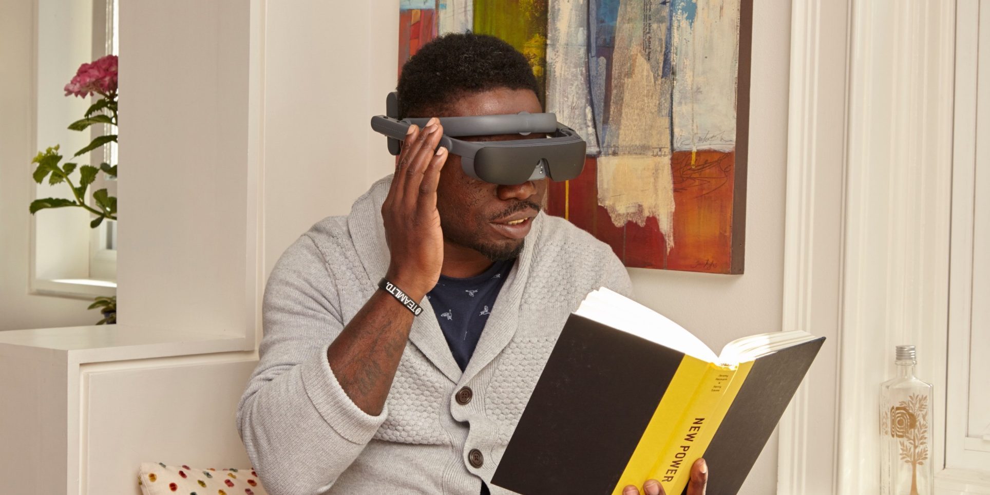 A man wearing eSight glasses reads a book.