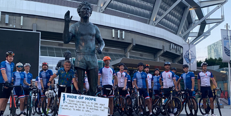 A bunch of bikers gathered around a statue of Terry Fox