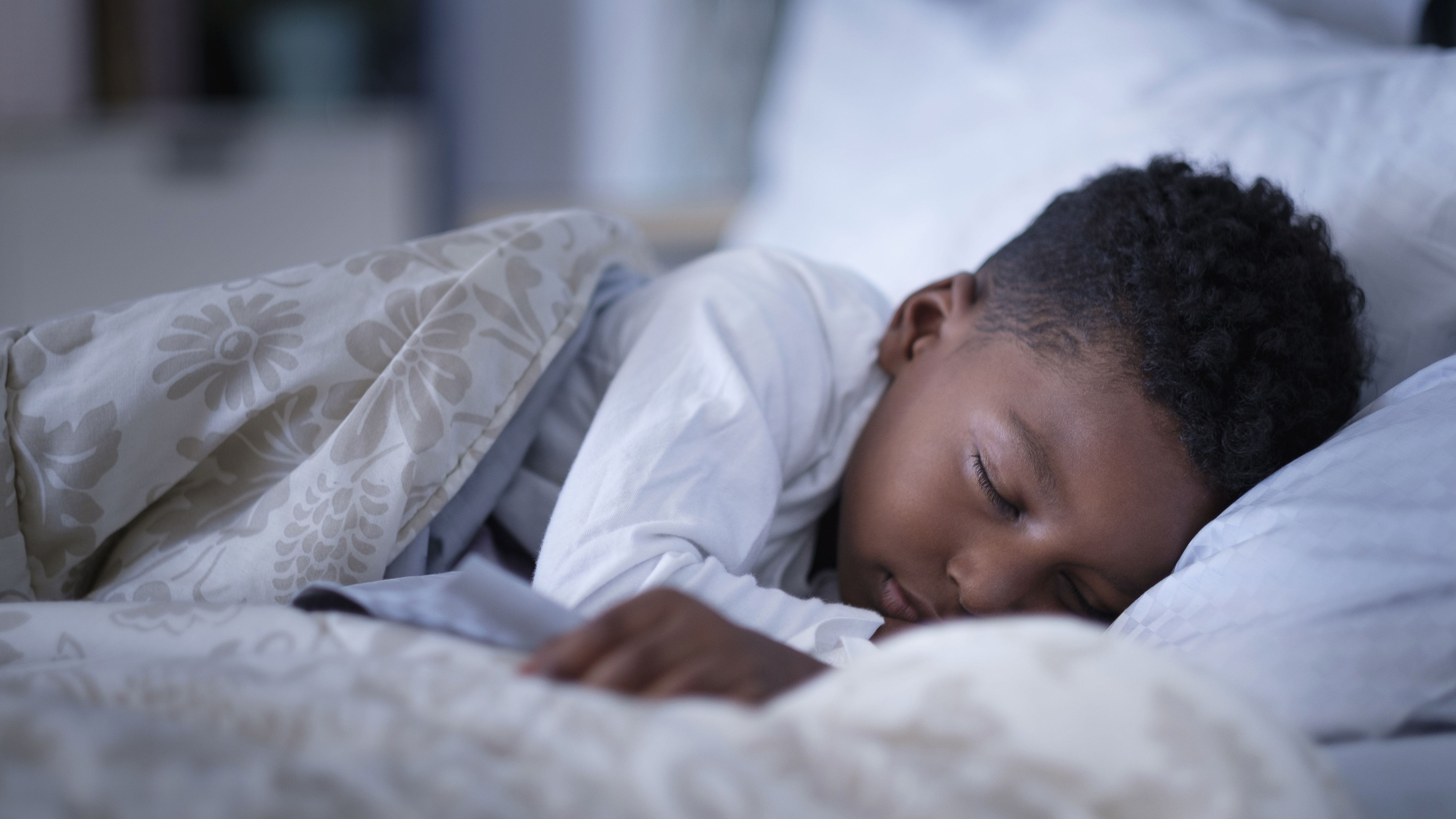 A little boy sleeping in a bed