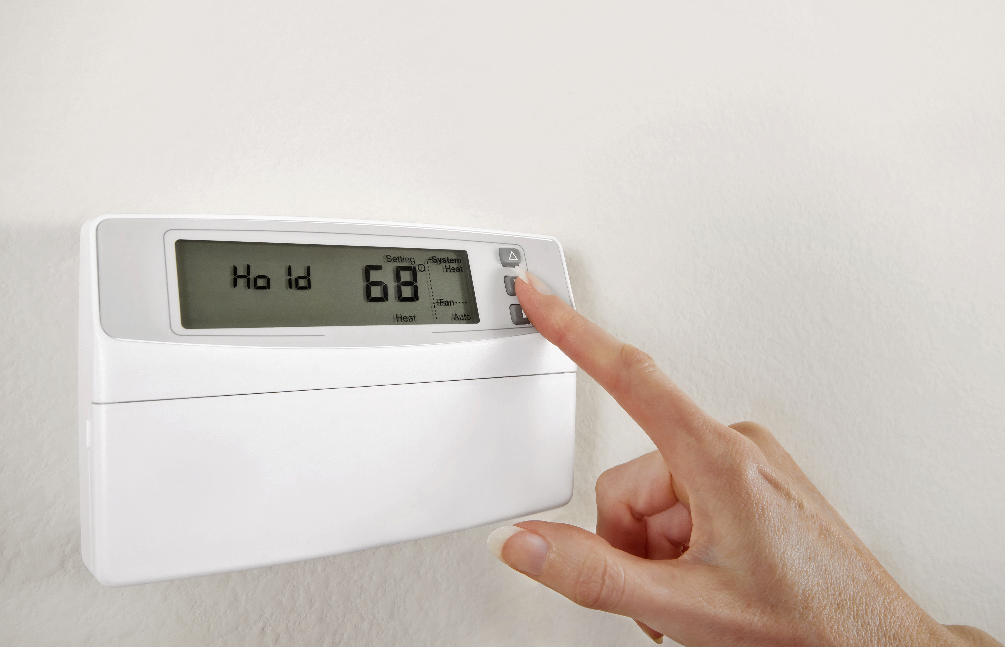 A person adjusting the thermostat