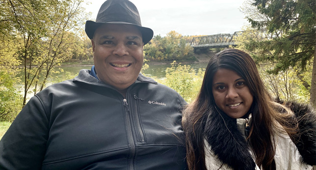 Kelly and Ramya sitting together outside smiling for a picture