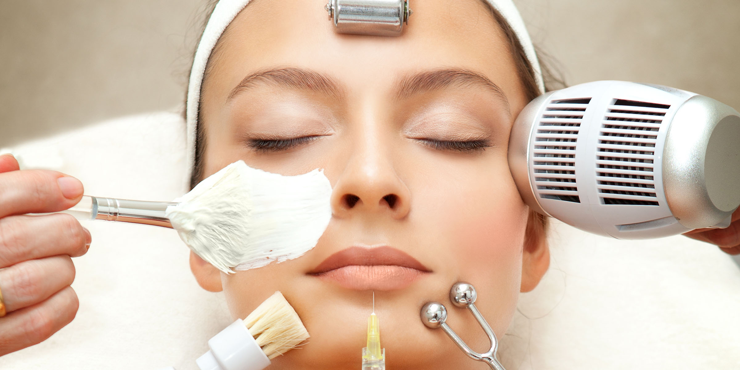 A variety of brushes and rollers arranged around a woman's face.