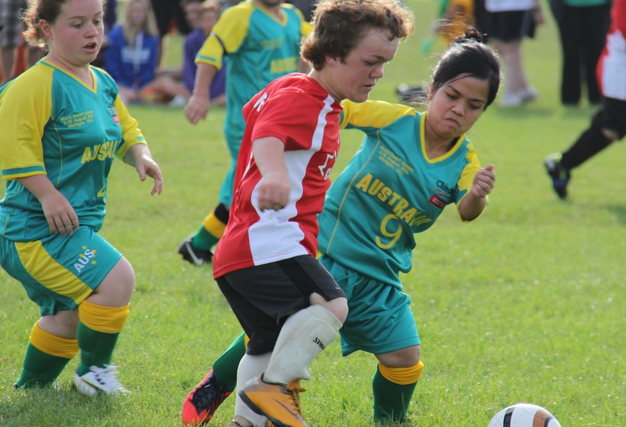 Two female soccer players on opposing teams fight for the ball during a match. 